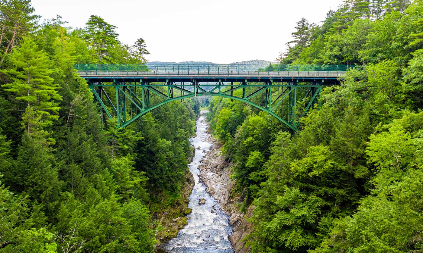 Photo of railroad bridge spanning across a river in wooded area